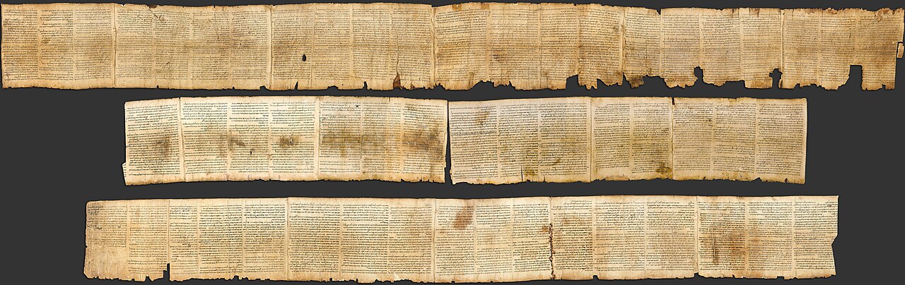 The Great Isaiah Scroll, one of the Dead Sea Scrolls — an aged parchment showing dense columns of ancient Hebrew script, photographed unrolled in a long horizontal panorama